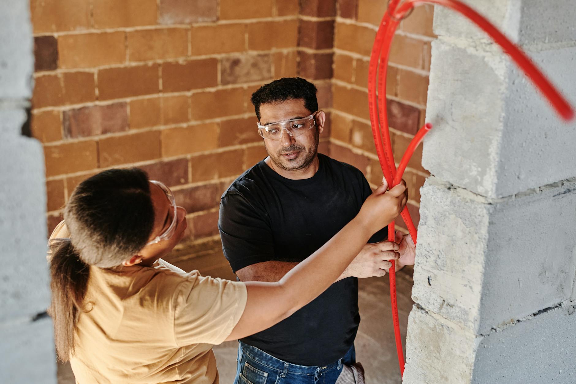 man and woman holding a red hose